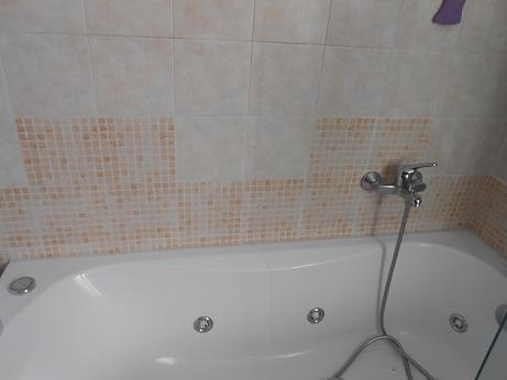 il bordino plastico e' contro la parete piastrellata  tra la vascastessa e la parete